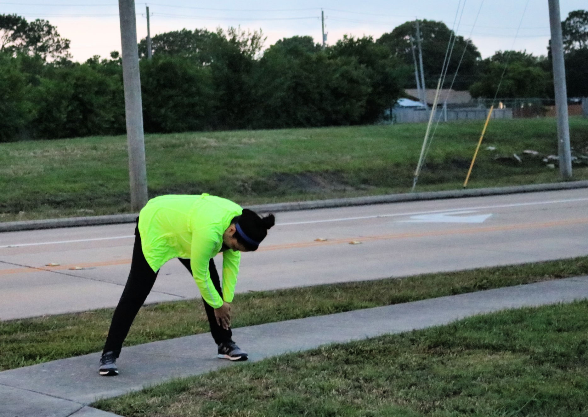 a woman in a jacket and pants stretching outside before a run